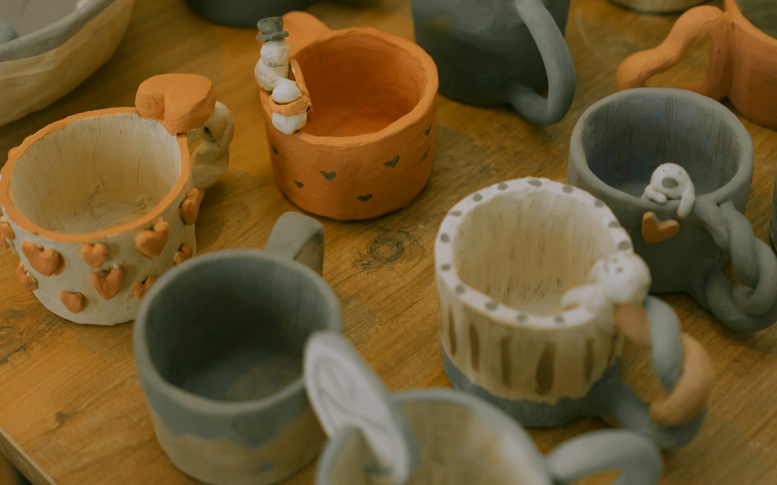 A wooden table topped with lots of ceramic cups