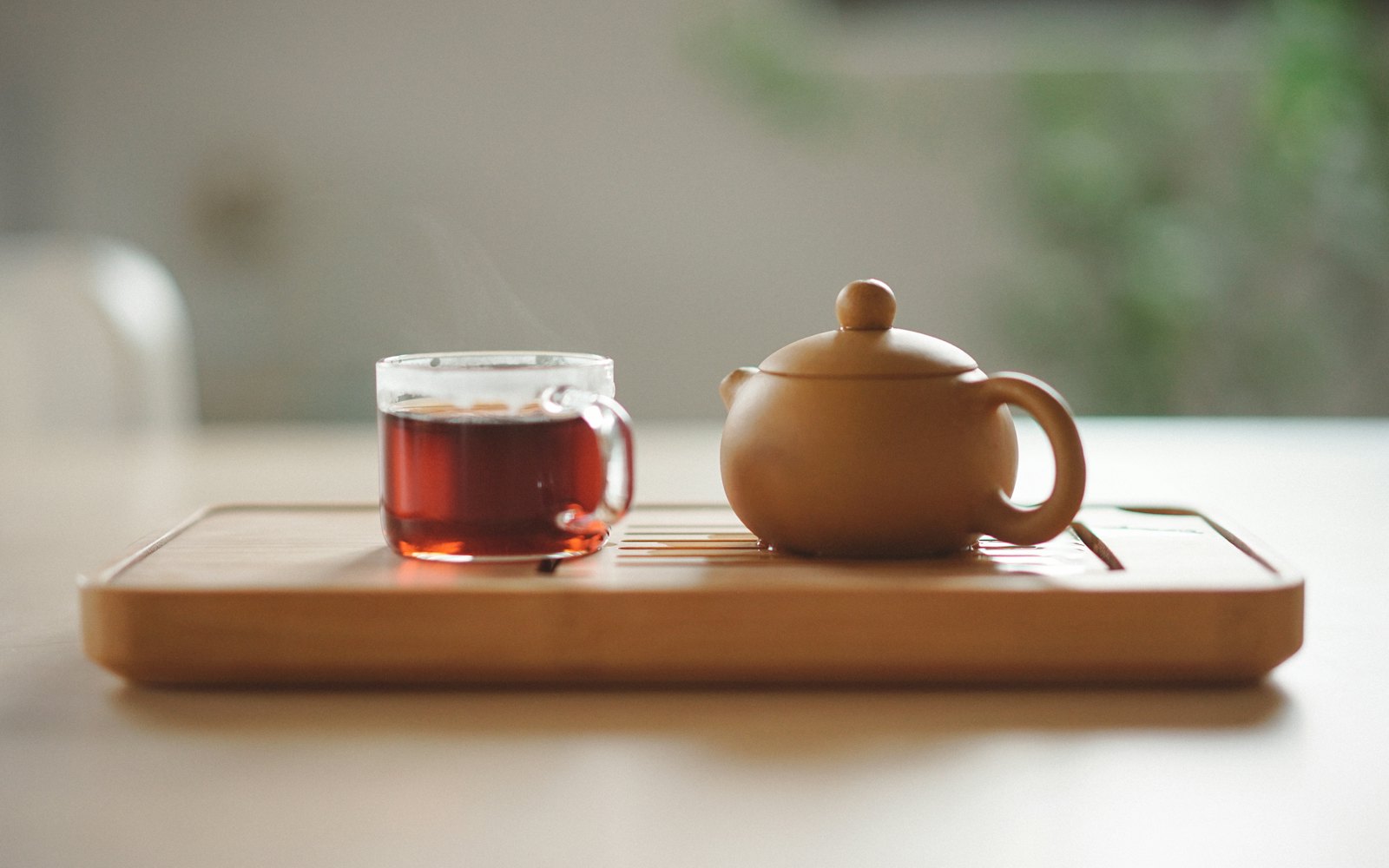 Clear glass cup with tea near brown ceramic teapot