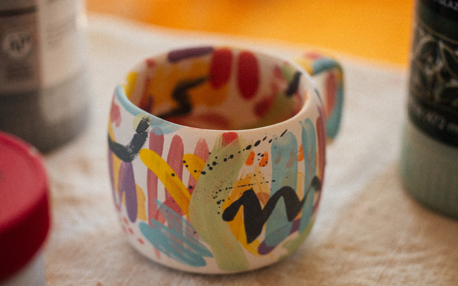 A ceramic mug with vibrant hand painted abstract patterns